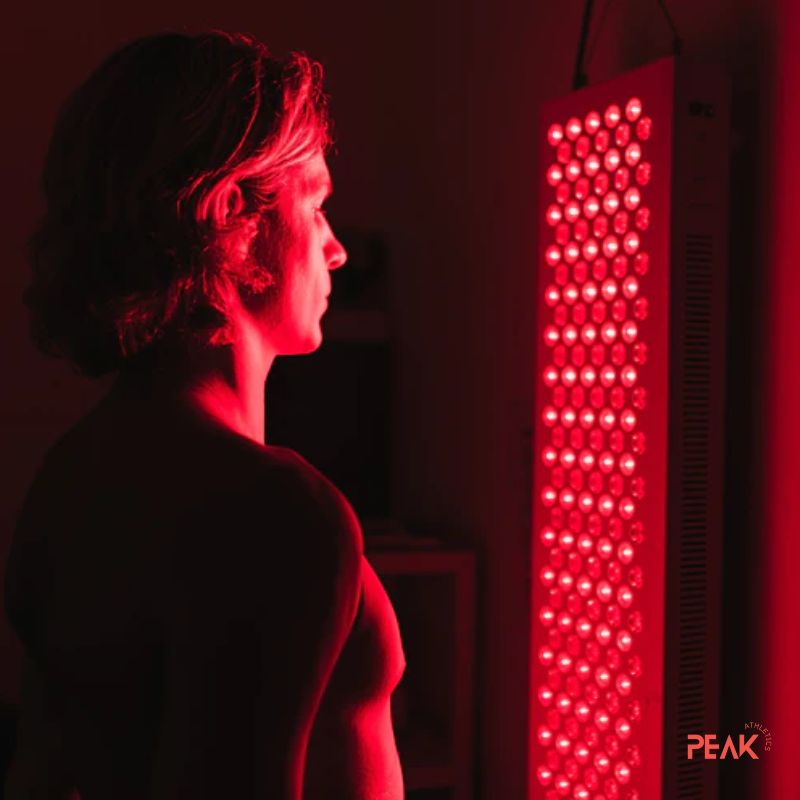 An image of a man enjoying a red light therapy session. The red lights are on. The room is dark