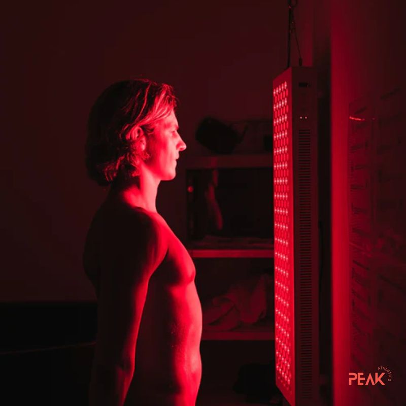 An image of a man enjoying a red light therapy session. The red lights are on. The room is dark