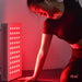 this is a photo of a woman enjoying a red light therapy session while exercising. Lights are on and the room is dark