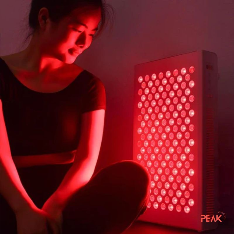 this is a photo of a woman enjoying a red light therapy session. She is sitting down and the lights are on and the room is dark