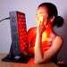 An image of a woman enjoying a red light therapy session. The red lights are on. The room is dark